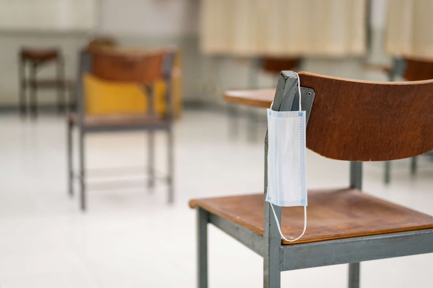 Medical face mask hanging on classroom chair