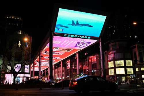 This picture shows a general view of a public big screen broadcasting news about China's military drills around Taiwan, outside a shopping mall in Beijing on April 1, 2025.