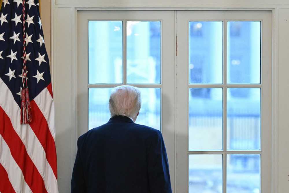 President Donald Trump looks through a window of the White House