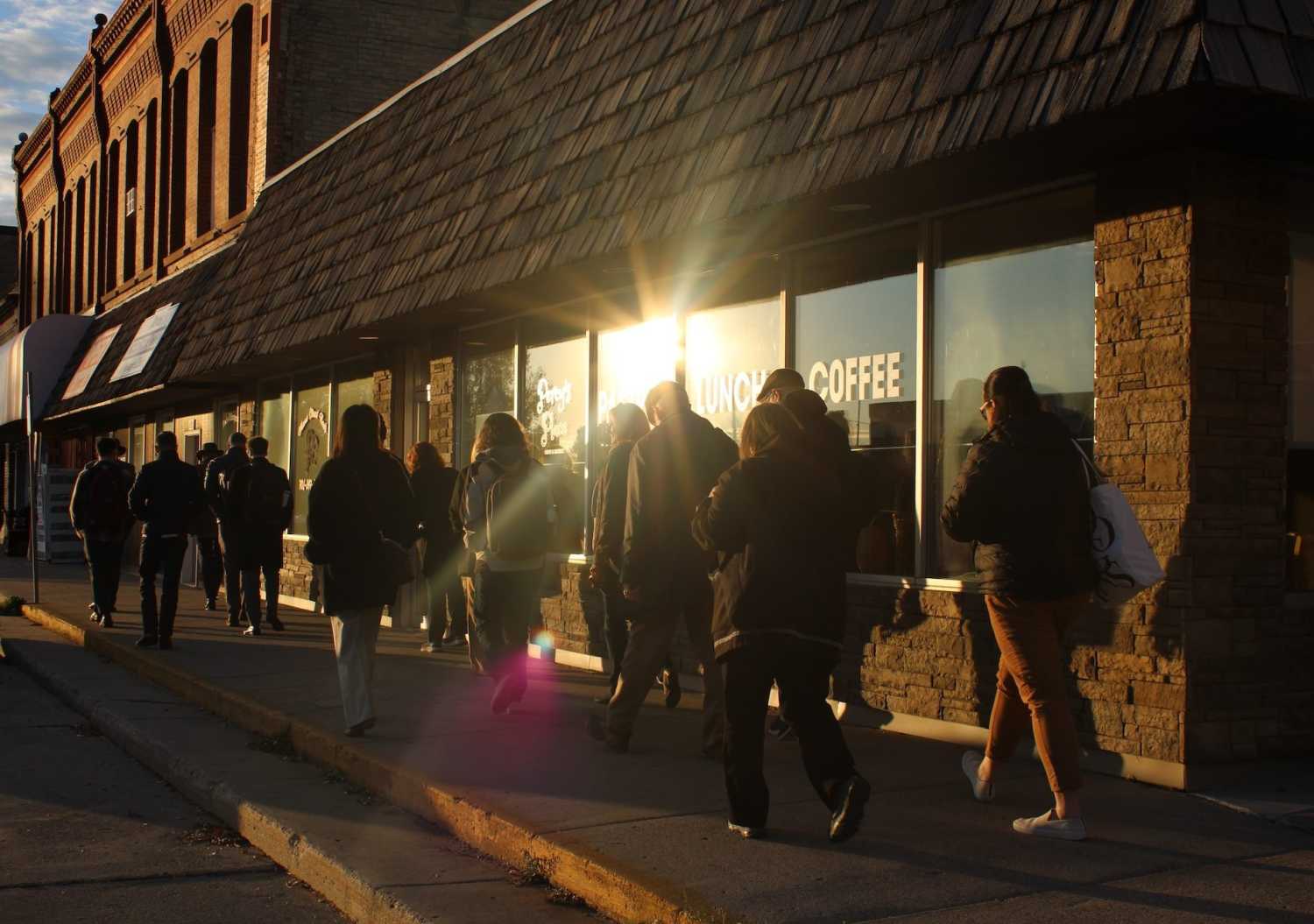 People walk along the sidewalk in front of a cafe