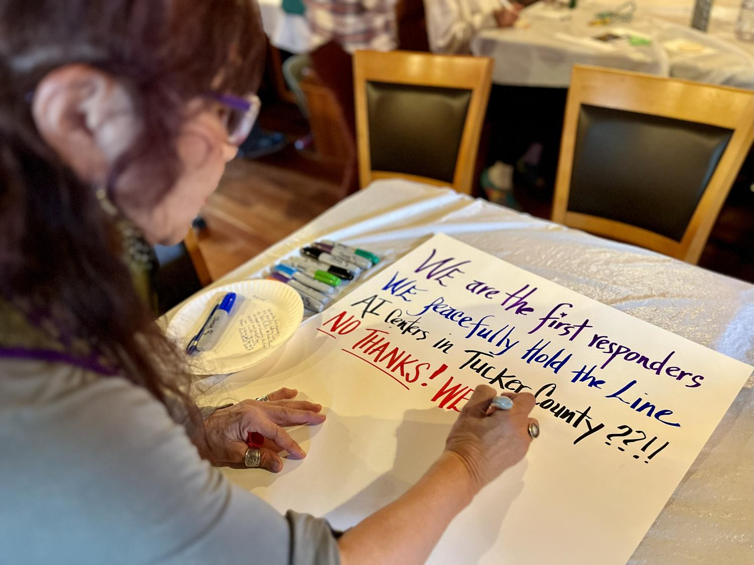 Tucker United member prepares a protest sign against a data center