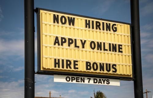 Billboard sign reading "Now hiring, apply online, hire bonus."