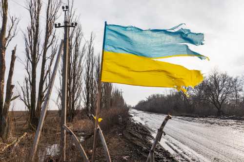 A torn but flying Ukrainian flag is seen along a road in the Donetsk region.