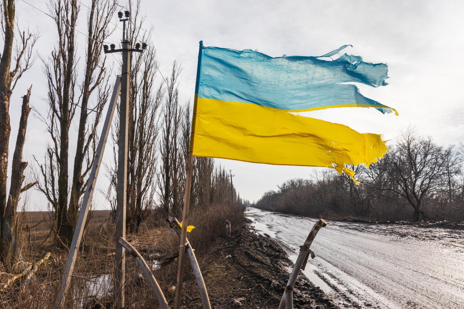 A torn but flying Ukrainian flag is seen along a road in the Donetsk region.