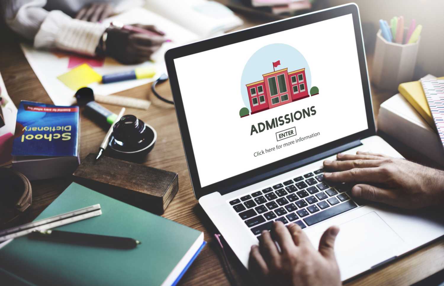 Person typing on a laptop with an Admissions page.
