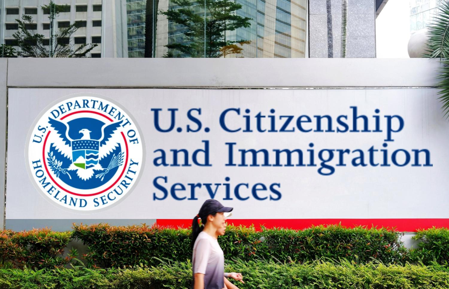 People walking in front of a DHS U.S. Citizenship and Immigration Services sign.
