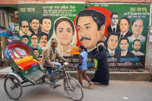 People pass by a large piece of political graffiti in Dhaka, Bangladesh.