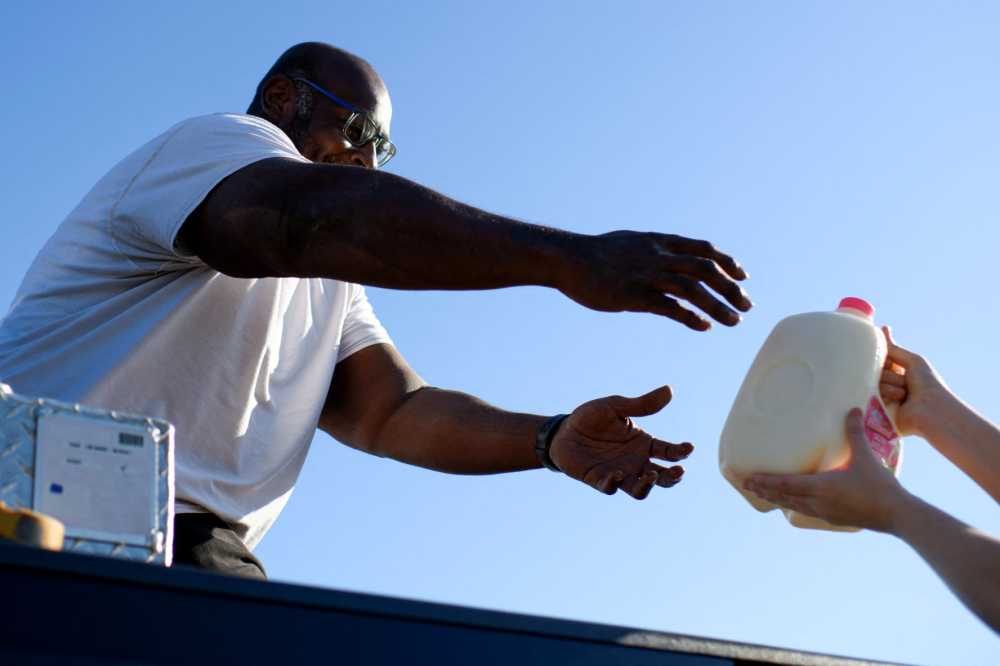 A Houston resident reaches for a jug of milk while getting free goods during a special food distribution by the Houston Food Bank Program at the NRG Stadium in Houston, Texas, on November 1, 2025.