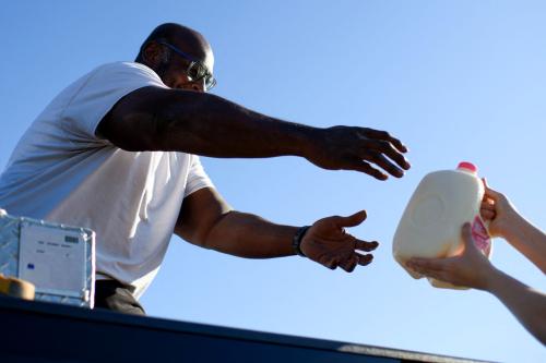 A Houston resident reaches for a jug of milk while getting free goods during a special food distribution by the Houston Food Bank Program at the NRG Stadium in Houston, Texas, on November 1, 2025.