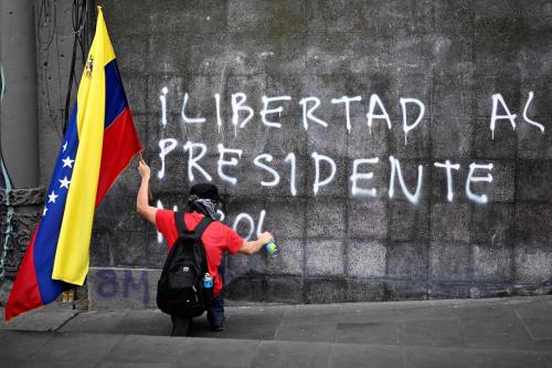 A demonstrator holding a Venezuelan flag paints a graffiti "Freedom for president Nicolas (Maduro) during a march in Mexico City on January 10, 2026, in support of deposed Venezuelan president Nicolas Maduro and his wife Cilia Flores and against possible US intervention in Mexico.