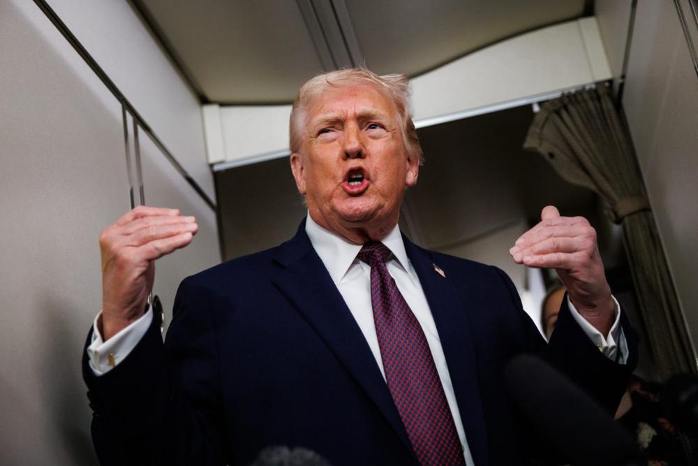 U.S. President Donald Trump takes questions from the members of the press aboard Air Force One on January 11, 2026 en route back to the White House from Palm Beach, Florida.