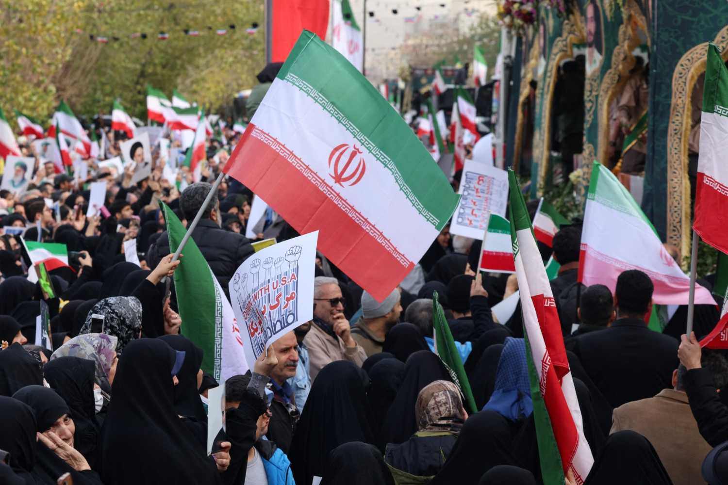 Iranians wave national flags during the funerals of security forces personnel killed in recent protests in Tehran on January 14, 2026.