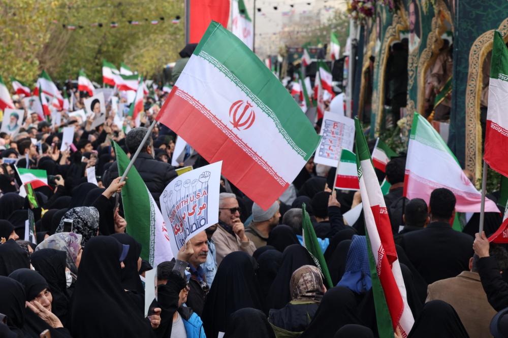 Iranians wave national flags during the funerals of security forces personnel killed in recent protests in Tehran on January 14, 2026.