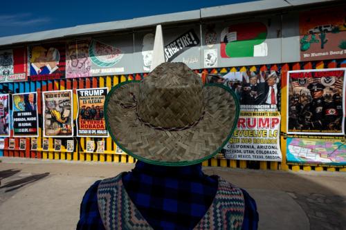 A man looks at banners against US President Donald Trump's migration policies by the "Alianza Migrante" advocate group hanging at the Mexico-U.S. border wall during a protest in Playas de Tijuana, Baja California state, Mexico, on February 2, 2026.