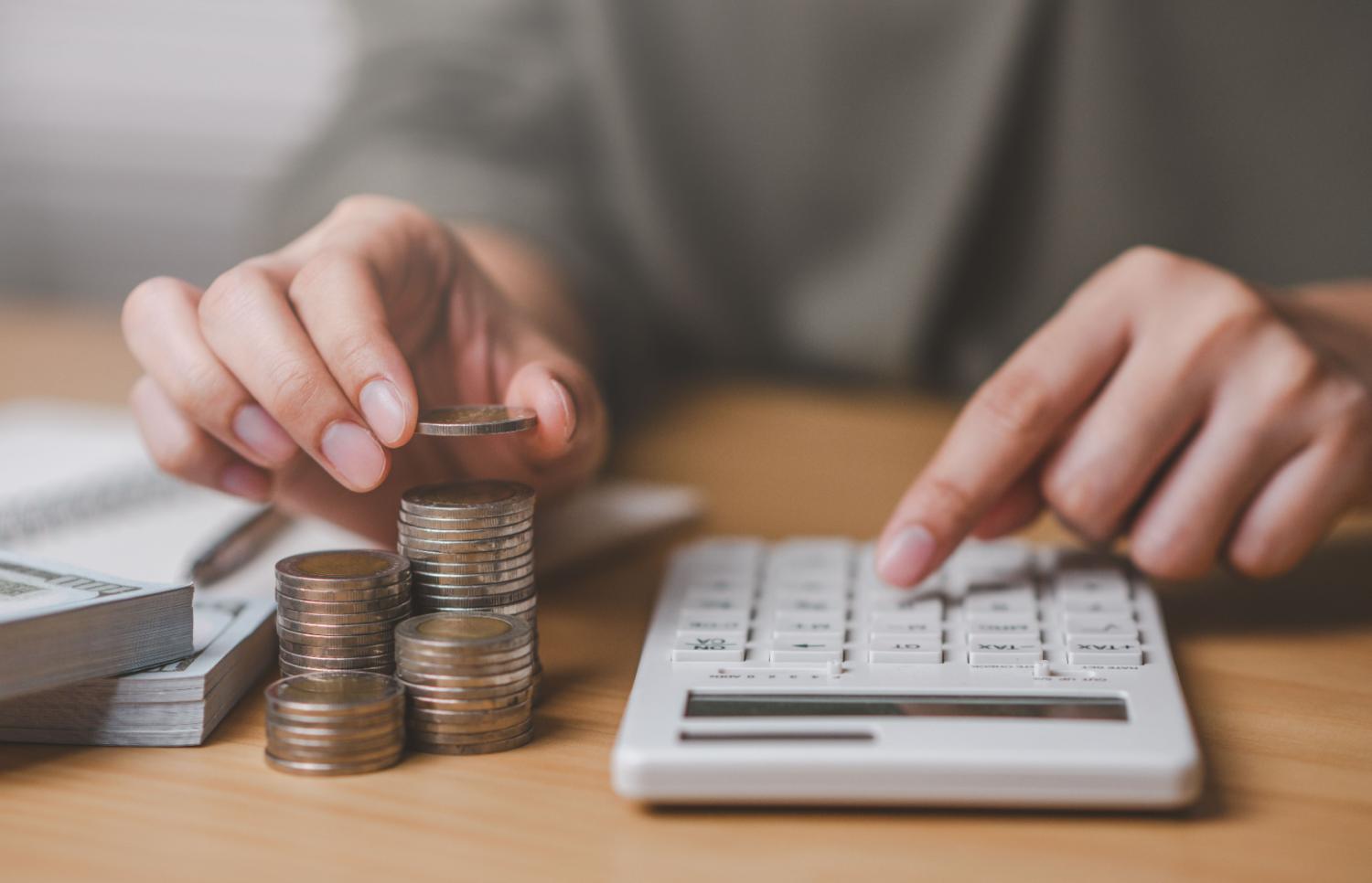 A person using a calculator and organizing coins.