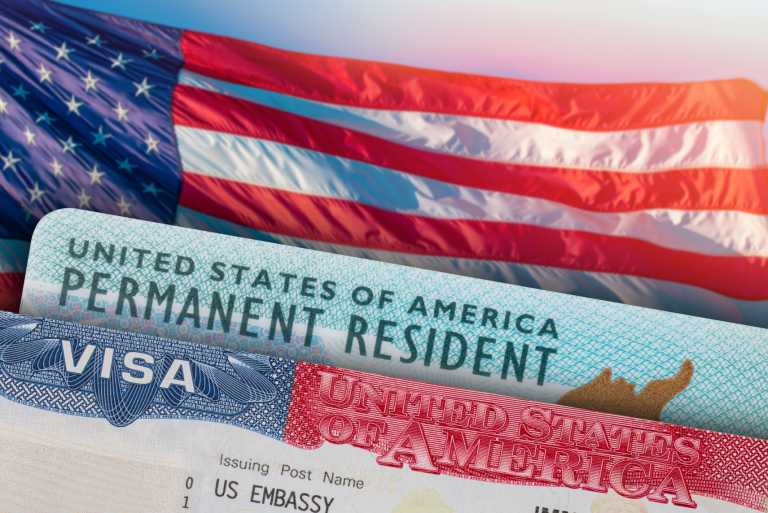 A US Flag pictured with a US Visa document and US Permanent Resident Card.