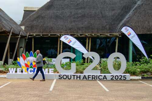 A man walks past a sign reading "G20 South Africa 2025."