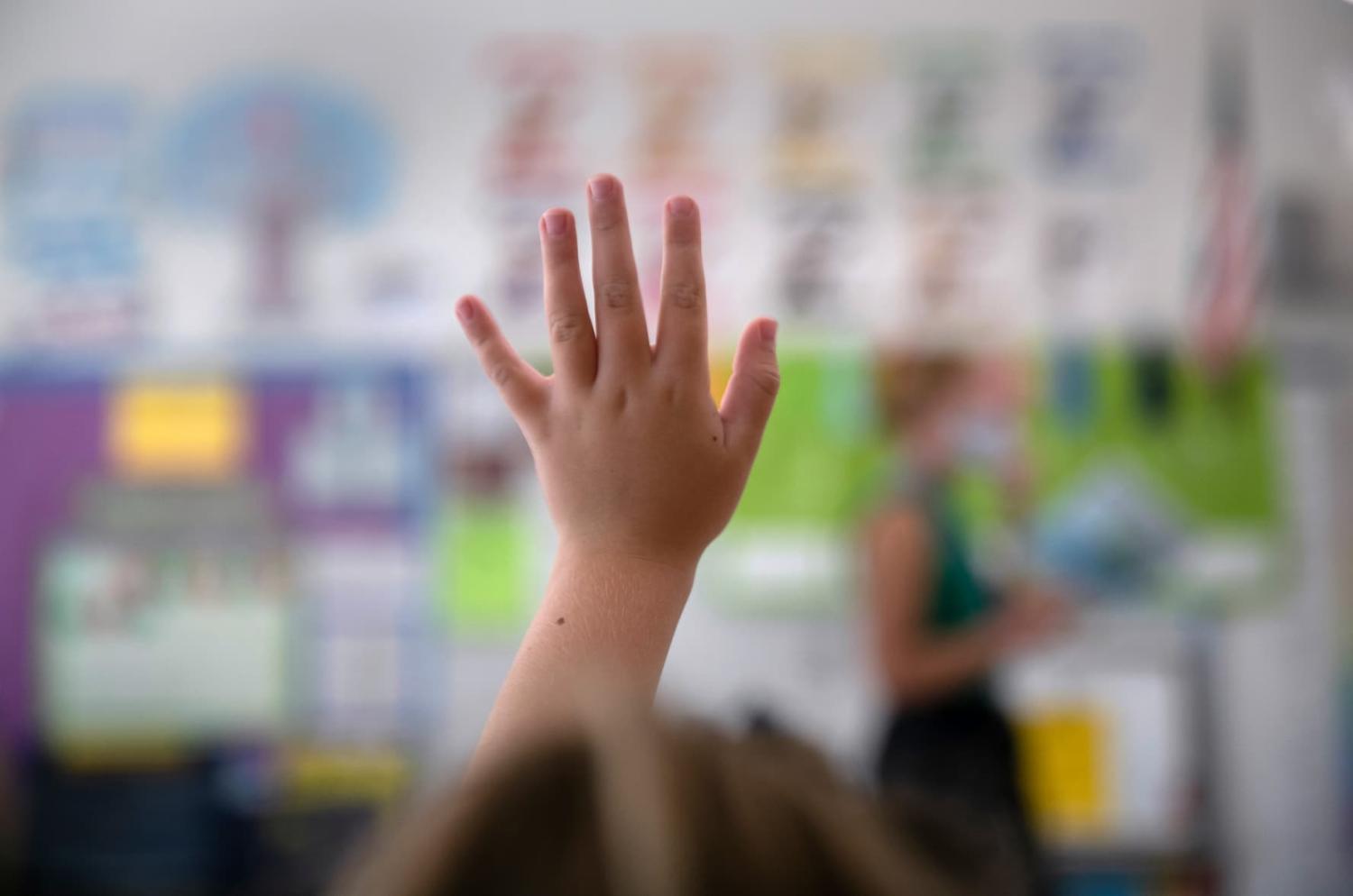 A student raises her hand during her first day of kindergarten on September 9, 2020, in Stamford, Connecticut.
