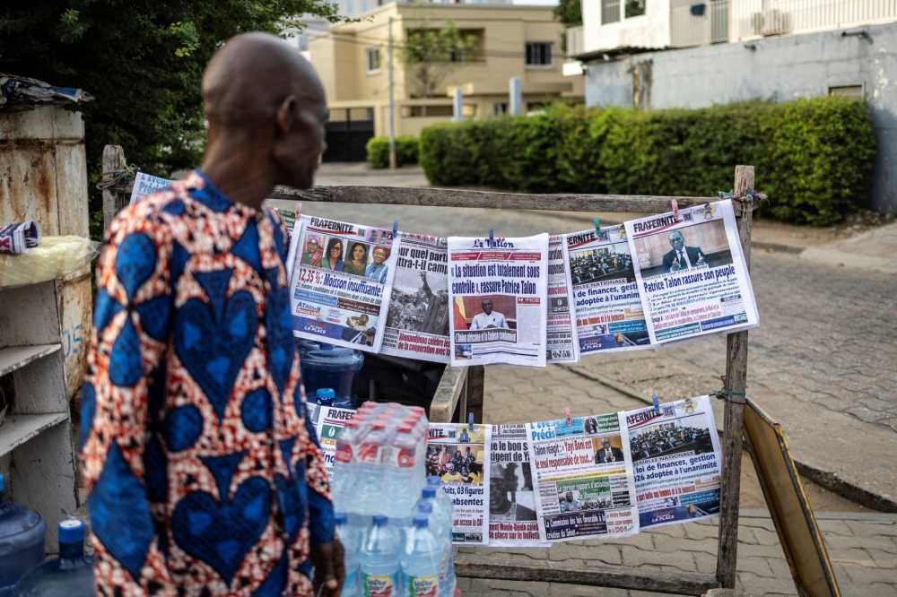 A vendor looks at newspapers displayed on a stall in Cotonou, on December 08, 2025. Benin's president said the "situation is completely under control" in his country after the government thwarted an attempted coup thanks to loyalist soldiers with support from Nigerian forces.