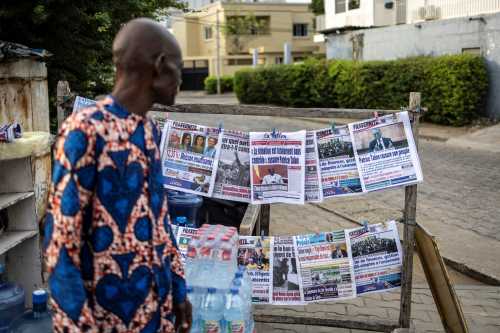 A vendor looks at newspapers displayed on a stall in Cotonou, on December 08, 2025. Benin's president said the "situation is completely under control" in his country after the government thwarted an attempted coup thanks to loyalist soldiers with support from Nigerian forces.