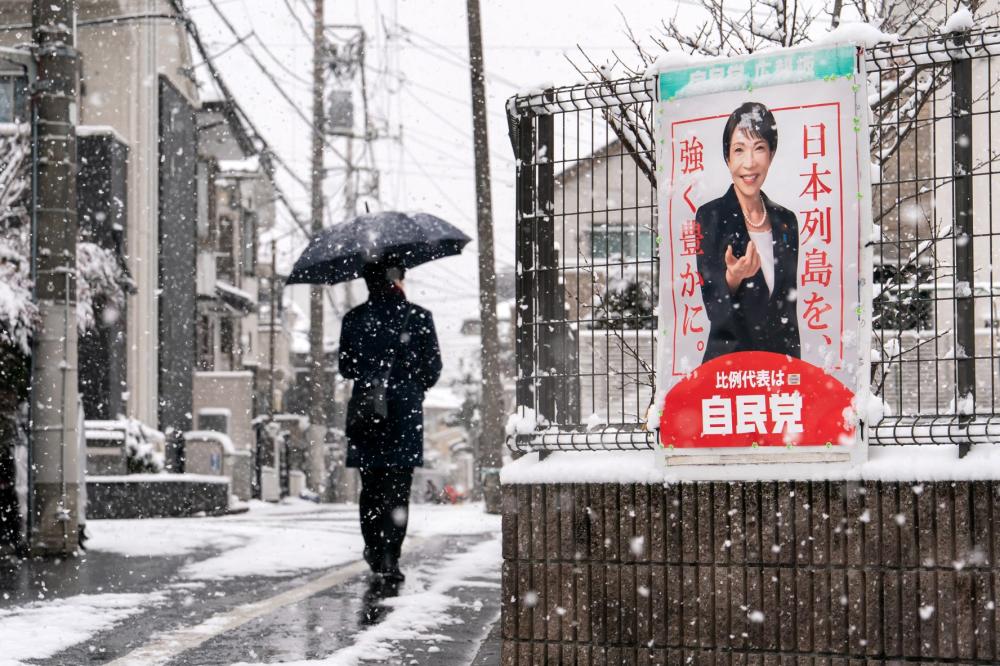 A pedestrian walks past an election poster bearing a photograph of Japanese Prime Minister and Liberal Democratic Party President Sanae Takaichi displayed near a polling station on February 08, 2026 in Tokyo, Japan.