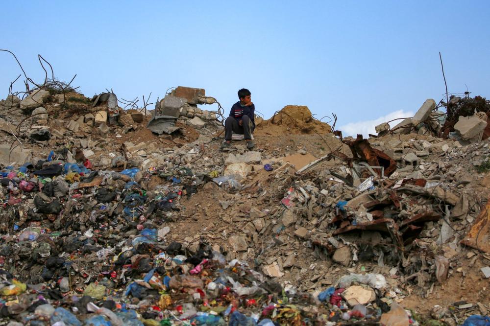 A boy sits on a mound of rubble and waste at the Maghazi camp for Palestinian refugees in the central Gaza Strip on February 11, 2026.
