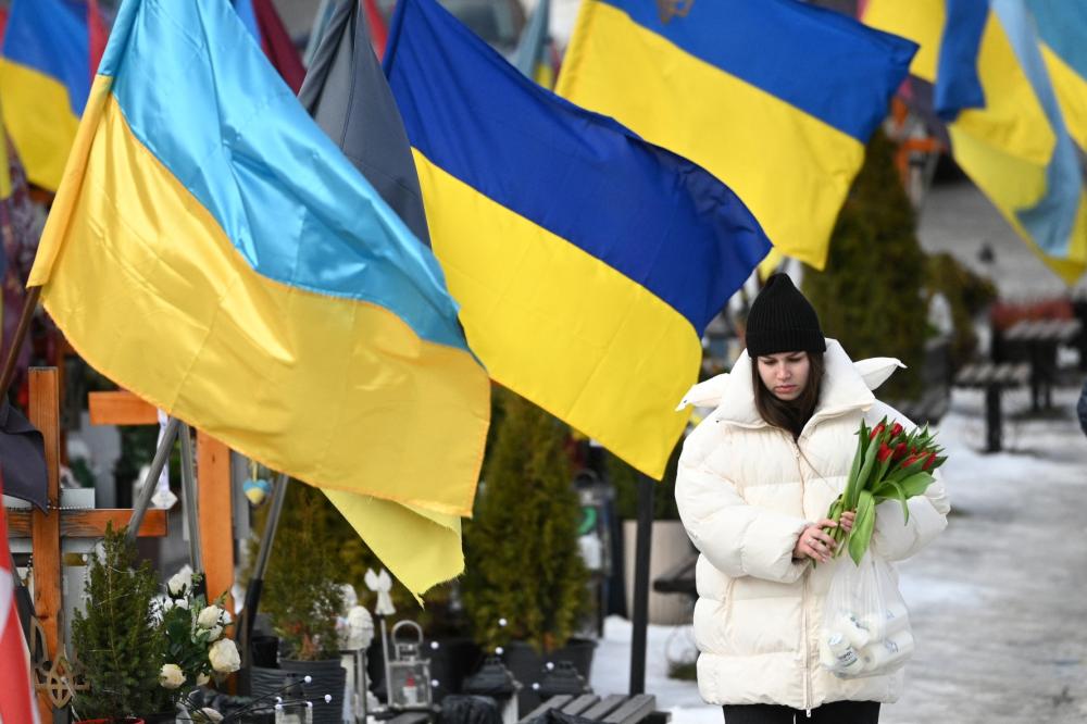 A mourner holds flowers on Valentine's Day at the Lychakiv Military Cemetery in Lviv, on February 14, 2026, amid the Russian invasion of Ukraine.