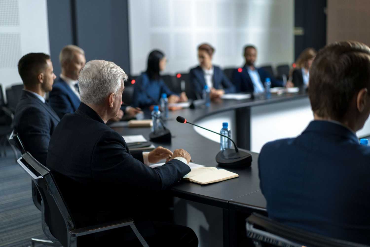 People dressed in suits sit around a conference table