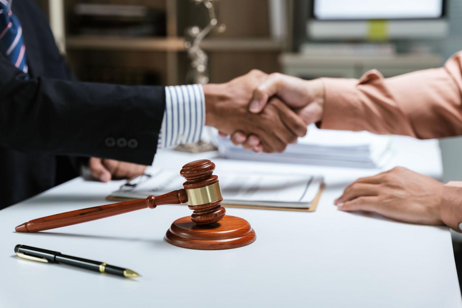 Two people wearing business clothes shake hands over a table