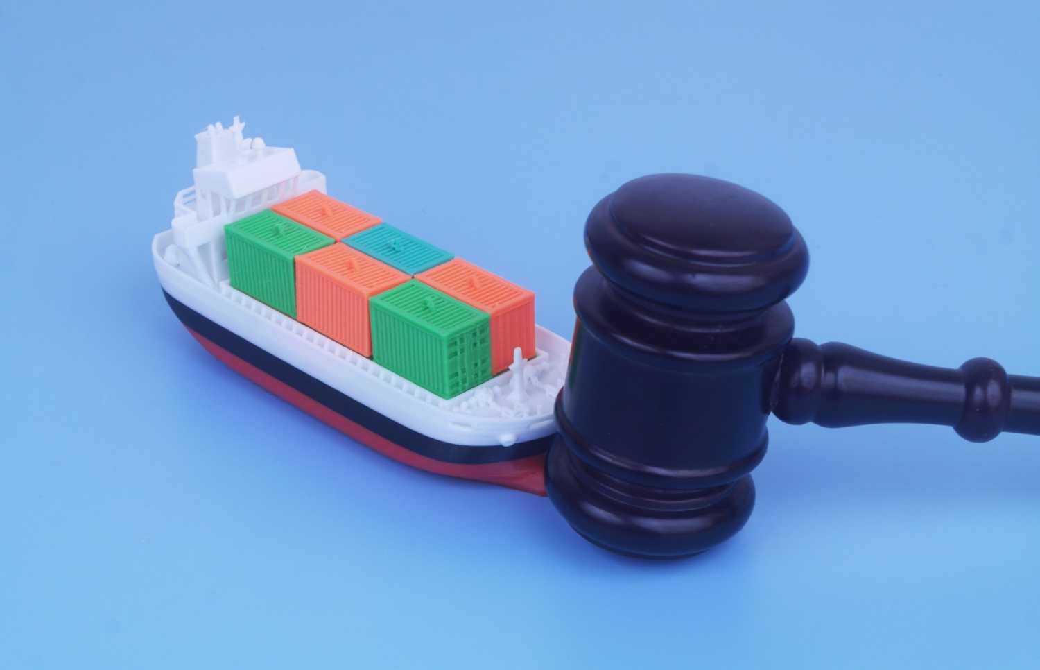 A gavel and a toy shipping container vessel.