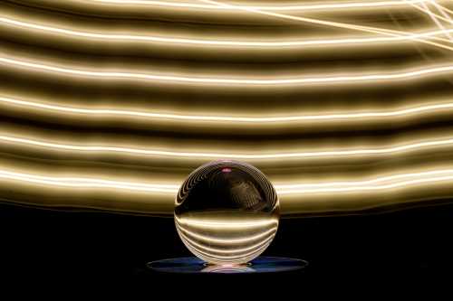 An abstract photo depicts a crystal ball influenced by an artistic colorful light play background.