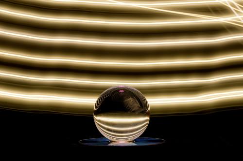 An abstract photo depicts a crystal ball influenced by an artistic colorful light play background.