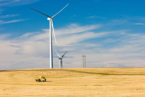 Wind turbines stand amidst the plains of eastern Montana near the Rocky Mountain front ranges of Glacier National Park USA.