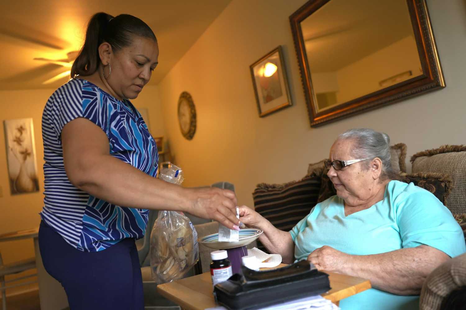 HAVERSTRAW, NEW YORK - MAY 05: Lidia Vilorio, a home health aide, gives her patient Martina Negron her medicine and crackers for her tea on May 05, 2021 in Haverstraw, New York.