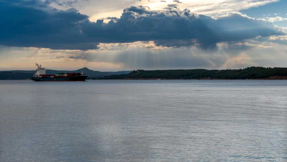 Canakkale, Turkey, November 12,2023: Cargo ship on the Dardanelles strait against evening sunset sky.