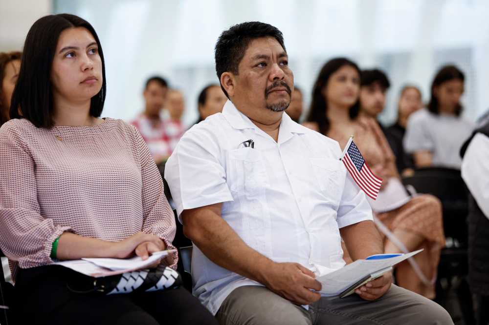 New U.S. citizens listen to a speech before taking the Oath of Allegiance and receiving their naturalization certificates during a formal ceremony at Midway International Airport in Chicago, Illinois, on June 25, 2025.