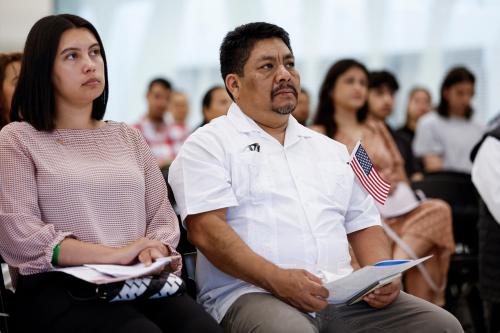 New U.S. citizens listen to a speech before taking the Oath of Allegiance and receiving their naturalization certificates during a formal ceremony at Midway International Airport in Chicago, Illinois, on June 25, 2025.