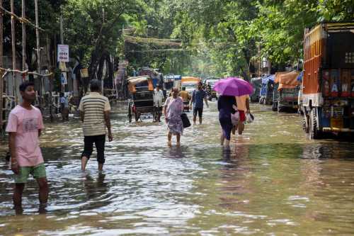 Commuters wade through floodwaters after heavy monsoon rains in Kolkata, India, on September 24, 2025.