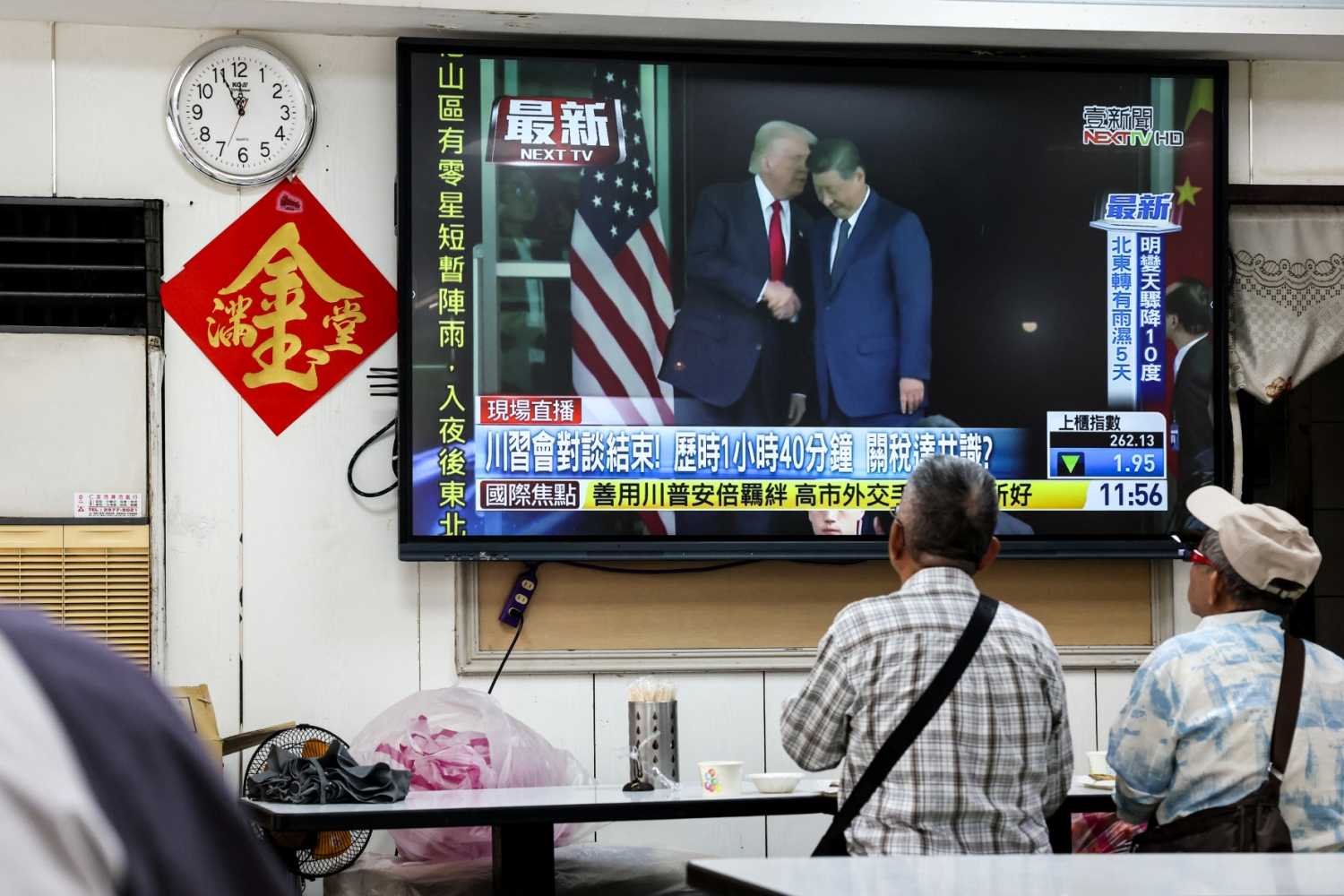 People watch a news programme in Taipei on October 30, 2025 showing the meeting of US President Donald Trump and China's President Xi Jinping in South Korea.