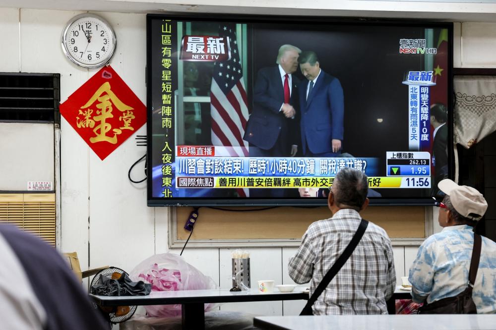 People watch a news programme in Taipei on October 30, 2025 showing the meeting of US President Donald Trump and China's President Xi Jinping in South Korea.