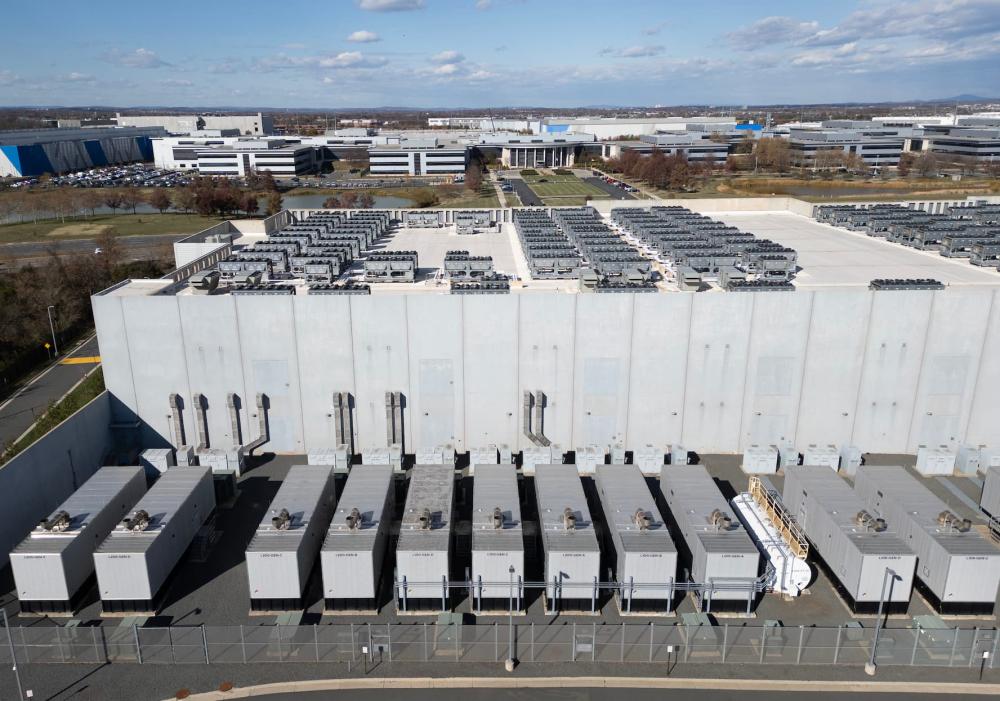 An aerial view shows cooling vent fans on the roof next to generators on the lower level of a Digital Realty data center in Ashburn, Virginia on November 12, 2025. Data centers are the physical infrastructure that make our digital lives possible, yet most people have never seen one up close or understand how they operate. Roughly 12,000 data centers are in operation in the world, with about half in the US, according to Cloudscene, a data center directory.