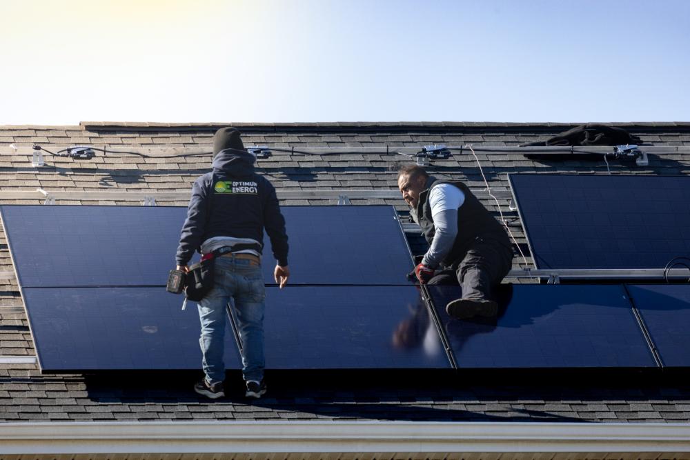 A team of solar panel installers work to install a new solar panel array before the Federal Tax Credit Expires.