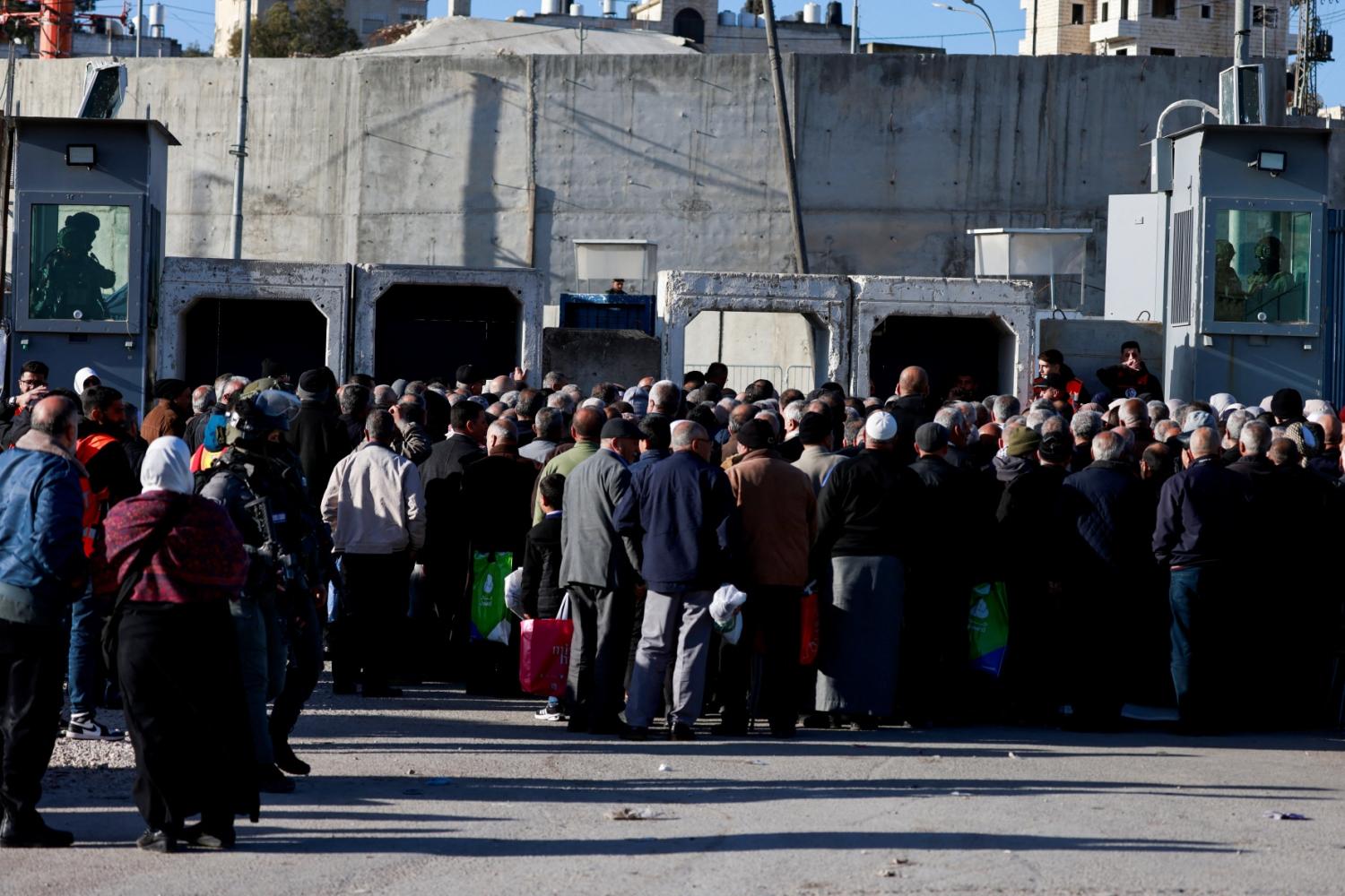 Israeli soldiers keep watch as Palestinian Muslims gather at the Qalandia checkpoint in the occupied West Bank city of Ramallah on February 20, 2026, to enter Jerusalem on their way to Al-Aqsa Mosque for the first Friday noon prayers of the Islamic holy month of Ramadan.
