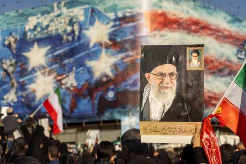 A protest holds a poster of Ali Khamenei as thousands of people gather in Enghelab Square for a pro-government demonstration after Iranian state media confirmed the death of Ayatollah Ali Khamenei on March 1, 2026 in Tehran, Iran.