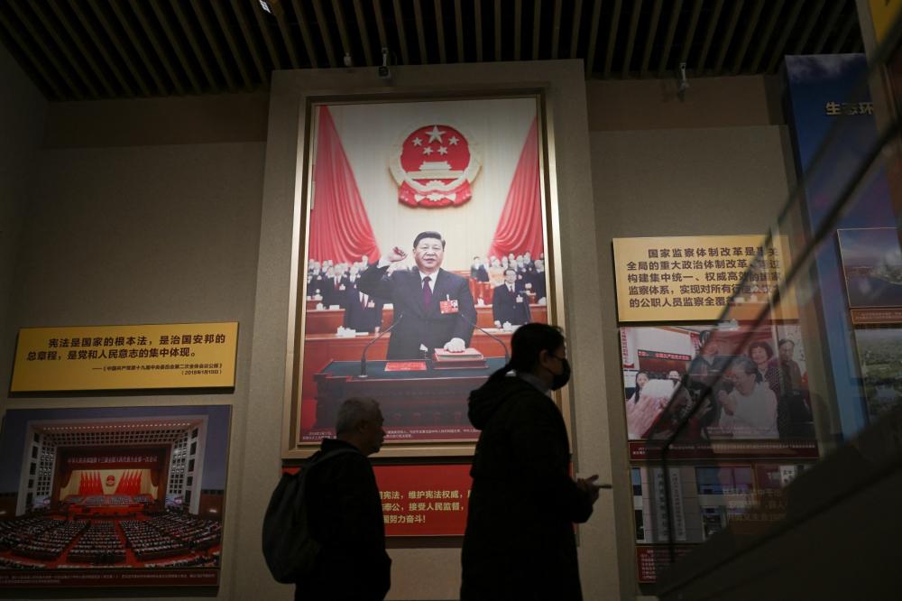 Visitors walk past portraits of China's President Xi Jinping at the Museum of the Communist Party of China in Beijing on March 1, 2026, ahead of the opening of the annual session of the National People's Congress (NPC).