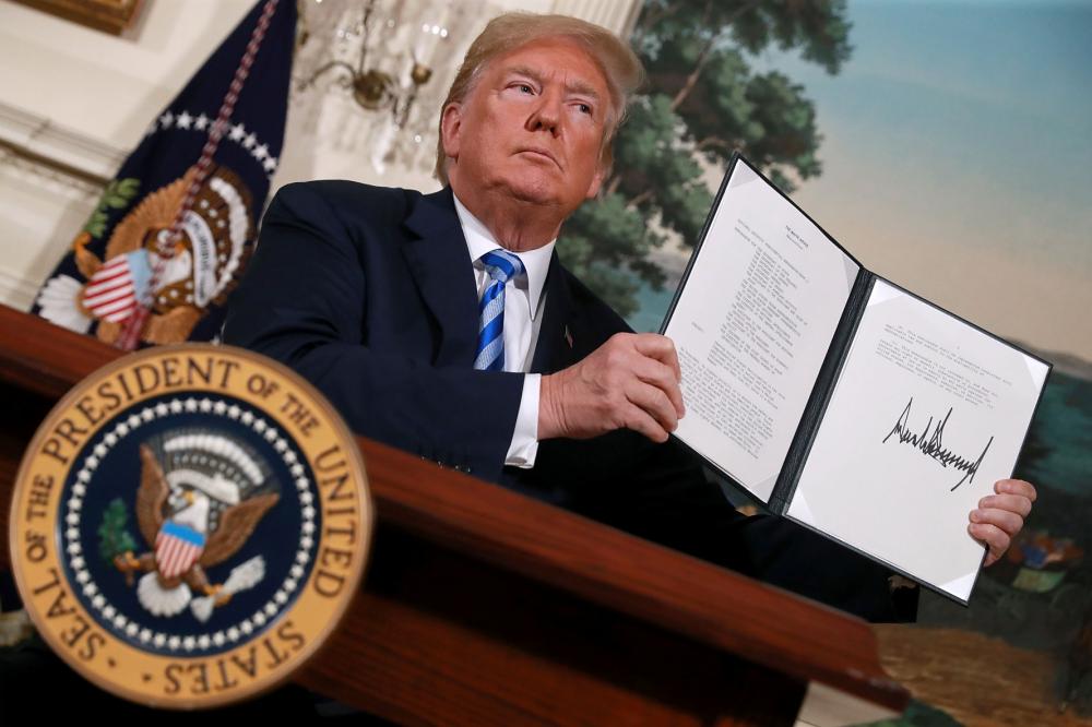 U.S. President Donald Trump holds up a memorandum that reinstates sanctions on Iran after he announced his decision to withdraw the United States from the 2015 Iran nuclear deal in the Diplomatic Room at the White House May 8, 2018 in Washington, DC.