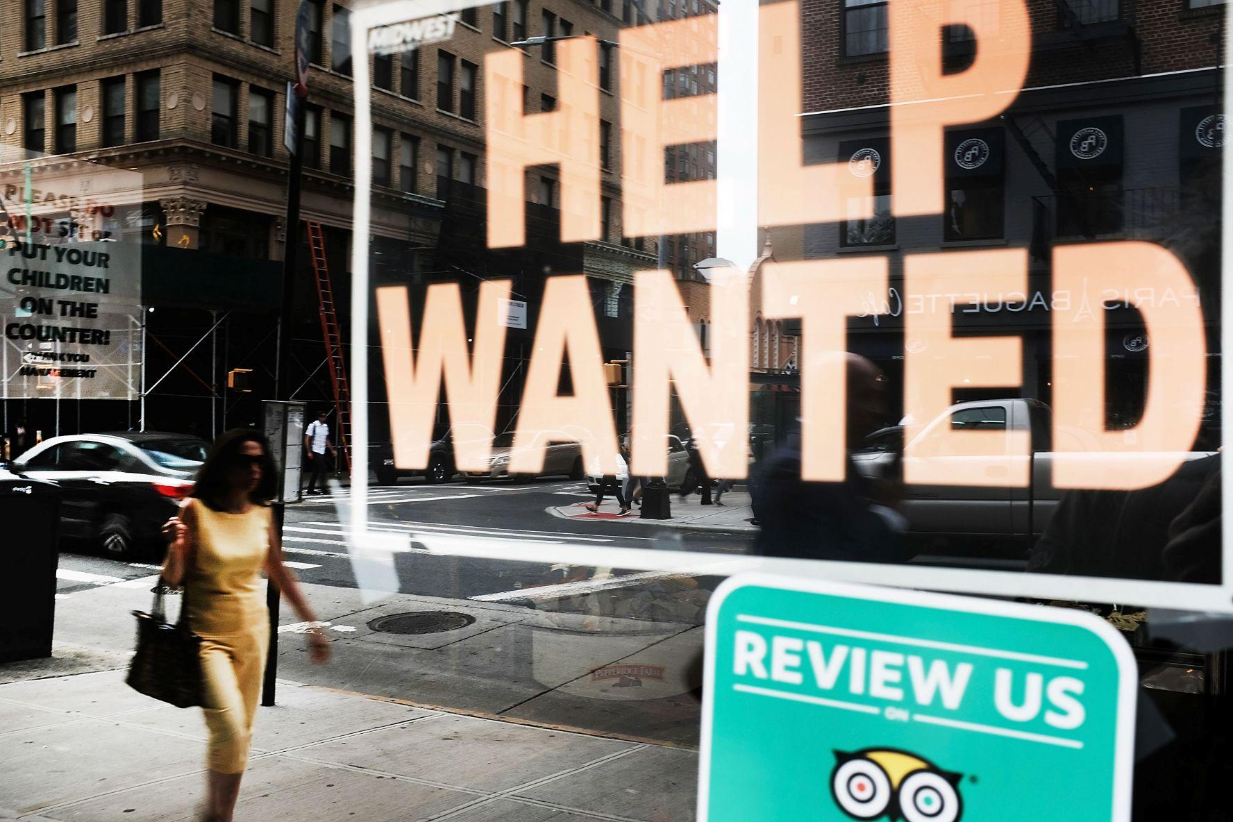 Illustration of a frozen US hiring market: help-wanted signs in shop windows on an empty street, symbolising posted openings that go unfilled.