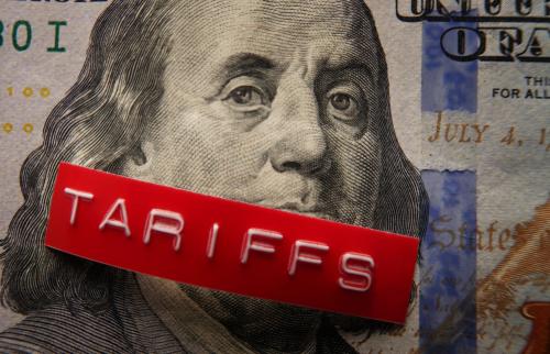 A red "tariff" label on a $100 bill.