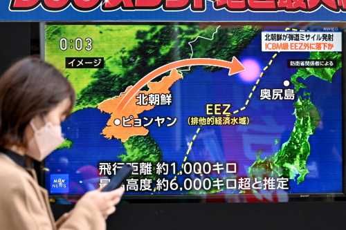 A pedestrian walks past a television screen broadcasting a news report on a North Korean missile launch, in Tokyo on December 18, 2023.