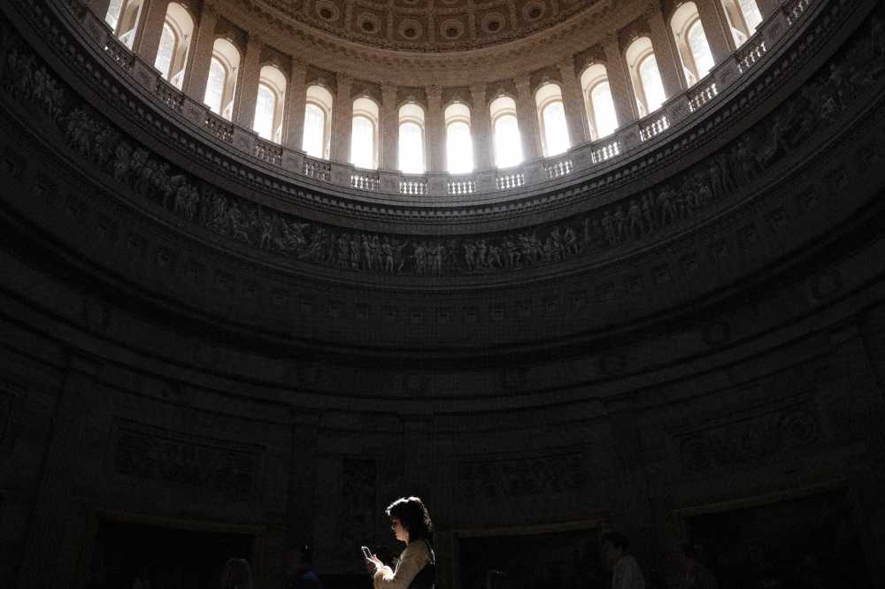 A woman looks at her cell phone while walking through the rotunda of the U.S. Capitol in Washington, D.C., on March 10, 2025